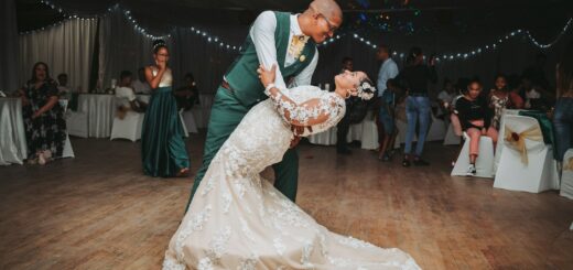 man in black suit jacket holding woman in white wedding dress