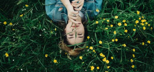 woman lying on grass ground with yellow petaled flowers