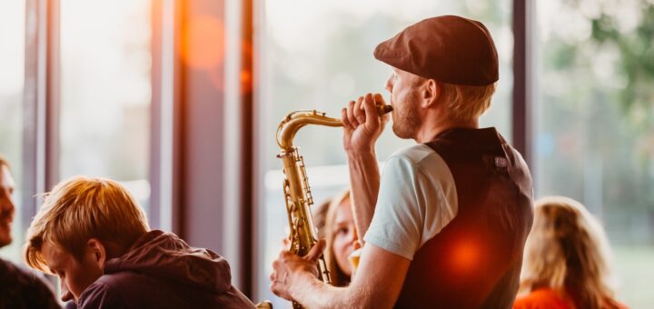 man in white crew neck t-shirt playing saxophone during sunset